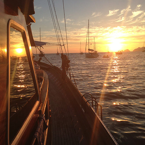 Tramonto sul mare visto dalla prua del caicco, con barche a vela all'orizzonte
