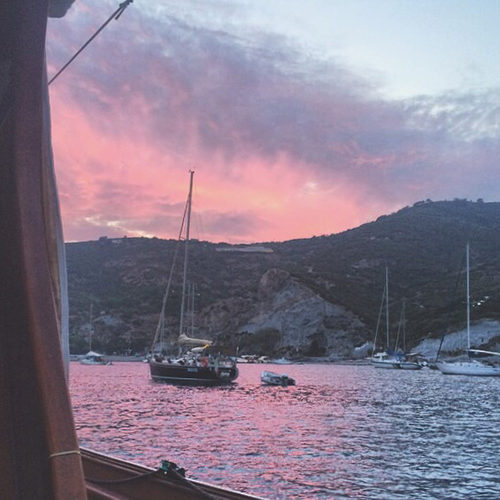Barca a vela alla fonda a Ponza sotto un cielo rosa al tramonto