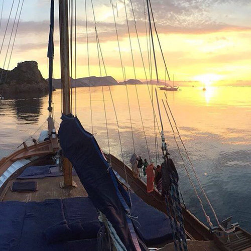 Tramonto dal ponte del caicco, con le vele raccolte e la costa di Ponza