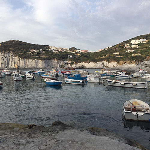 Barche ormeggiate in una baia di Ponza sotto le falesie bianche