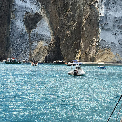 Barche nell'acqua azzurra sotto le falesie bianche di Ponza