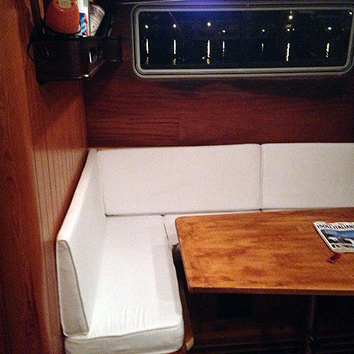 Dinette del caicco con divano bianco ad angolo e tavolo in legno