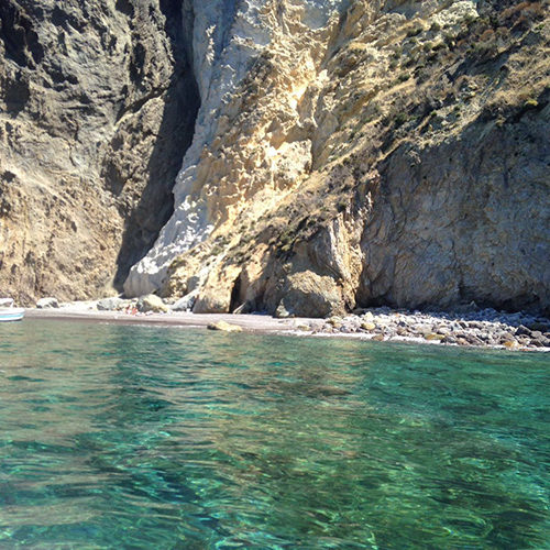 Acqua cristallina davanti a una spiaggetta sotto le rocce di Palmarola