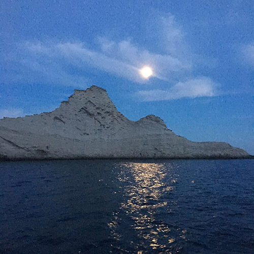 La luna sopra il profilo roccioso di Palmarola, riflessa sul mare