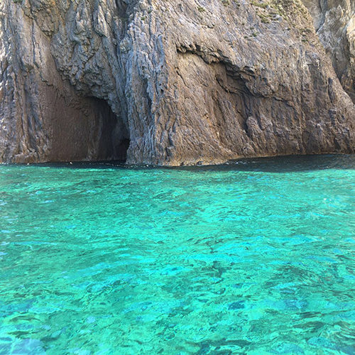 Grotte nella roccia sopra il mare turchese di Palmarola